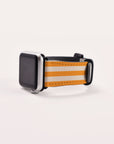 A sleek silver smartwatch featuring a blank screen is adorned with the Orange Stripes Vegan Leather Apple Watch Band, which showcases vibrant orange, white, and tan stripes. It rests elegantly on a simple white surface.