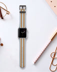 A smartwatch with a timeless clock face and the Brown and Blue Stripes Vegan Leather Apple Watch Band lies elegantly on a white desk, surrounded by a planner, glasses, pen, paperclip, and notepad.