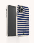 The Navy Stripes Eco-Friendly Biodegradable Phone Case is a beige smartphone case with dark blue horizontal stripes, featuring a camera cutout and a small green logo at the bottom. The product is displayed against a plain white background.