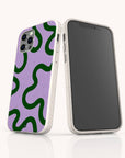 Two smartphones in white cases; one displays the front screen, while the other showcases the Purple and Green Swirl Eco-Friendly Biodegradable Phone Case, which features a purple background with bold, wavy green lines.