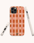 Three views of the Terracotta Watercolour Checker Eco-Friendly Phone Case are shown on a white background. This compostable, eco-friendly case features a red and pink checkerboard pattern with a small horseshoe logo at the bottom center, and is compatible with both iPhone and Samsung devices.