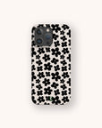 A smartphone with a Black Flower Power Eco-Friendly Phone Case, which features a pattern of black flowers on a white background, displayed against a plain light-colored backdrop.