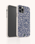The Ocean Waves Eco-Friendly Phone Case, in a cream color with wavy blue line patterns inspired by ocean waves, is shown on a smartphone angled to display both the front screen and the artfully designed back of the case.