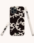 The Cow Print Eco-Friendly Phone Case is shown on a smartphone in a stylish black and white cow print design, captured from the back and sides against a plain light background. This case is compatible with both iPhone and Samsung devices.