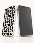 Two smartphones with matching Black Flower Power Eco-Friendly Phone Cases featuring a black floral pattern; one phone displays the retro floral case design on the back, while the other shows its blank black screen facing forward.