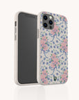 The Pink and Blue Coquette Flowers Eco-Friendly Biodegradable Phone Case features pastel floral patterns with pink and blue coquette flowers and blue ribbons on a light background, shown with a phone partially inside to display its design.