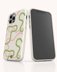 Two smartphones in off-white, eco-friendly phone cases showcase the Green and Pink Swirl Lines Eco-Friendly Phone Case, featuring a vibrant pink and green abstract squiggly design. One case displays the back and camera, while the other reveals a blank screen. Both are upright on a white surface—carefully crafted to stylishly fit your iPhone or Samsung Galaxy while prioritizing sustainability.
