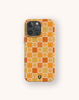 The Orange Flower Check Eco-Friendly Phone Case features an orange and beige checkerboard with white and orange flowers, a green “U” logo, and fits iPhone and Samsung Galaxy.