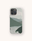 Blue Watercolour Landscape Eco-Friendly Phone Case, featuring a minimalist design of green mountains and a river under a cloudy sky, shown on a light background with an iPhone.