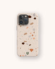 The Terrazzo Print Eco-Friendly Phone Case in beige, with colorful brown, pink, and gray speckles, is shown on a smartphone against a plain off-white background.