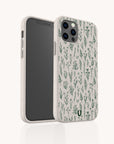 The Green Wild Flowers Eco-Friendly Phone Case is biodegradable, features a beige background with a green botanical pattern and a small green horseshoe logo, and fits iPhone and Samsung Galaxy models.