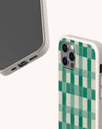 Two smartphones in Eco-Friendly Phone Cases: one features the Green Watercolour Checker pattern, the other shows its blank screen and charging port. Made from biodegradable materials and compatible with iPhone and Samsung Galaxy.
