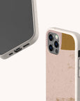 Two smartphones with Caramel Abstract Strokes Eco-Friendly Phone Cases in beige are displayed—one reveals the screen and charging port, while the other showcases the back, featuring gold and pink accents near the camera. These cases offer sustainable protection compatible with both iPhone and Samsung devices.