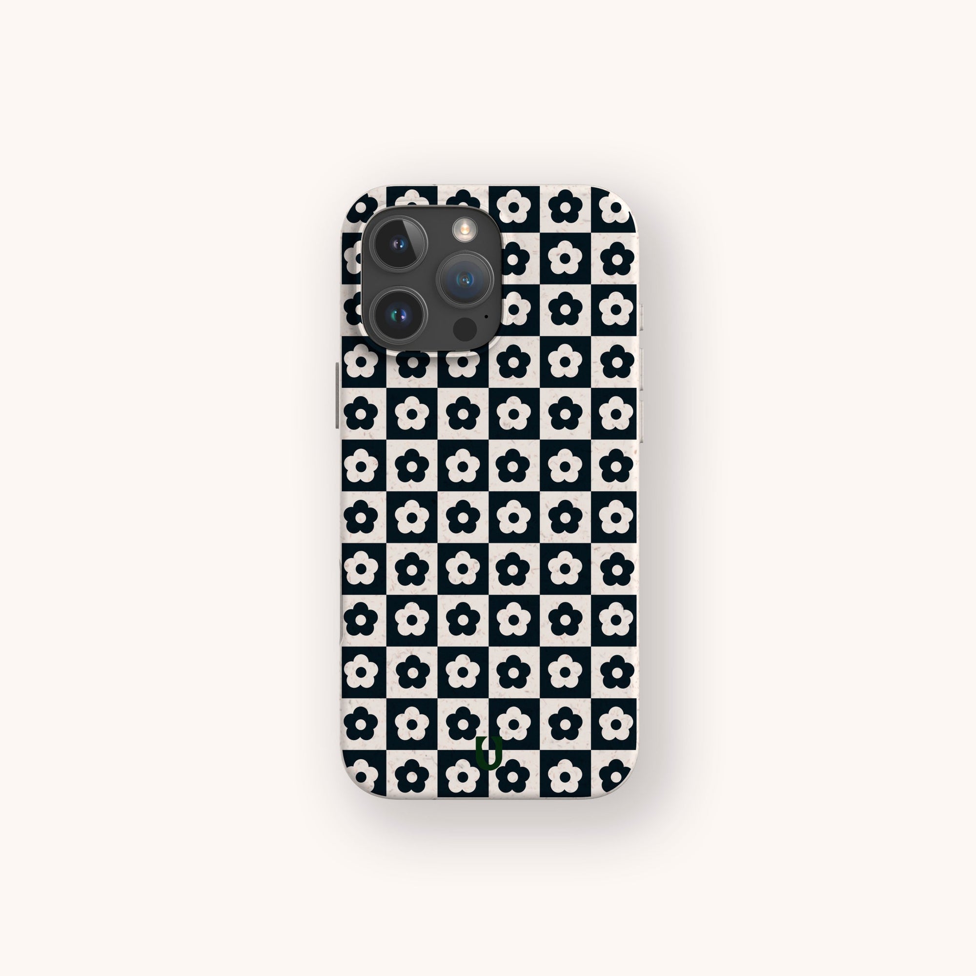 A smartphone with the Black Flower Checker Eco-Friendly Phone Case, featuring a black and white checker design of white flowers with black centers, is shown from the back on a light background.