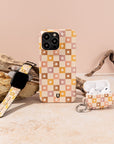 The iPhone, Apple Watch, and AirPods are showcased on a stone surface with driftwood accents in the background, each adorned with the Star Pink Checker Eco-Friendly Phone Case. This case is ideal for anyone looking to express their style while choosing a sustainable option.
