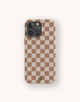 The Almond Checker Eco-Friendly Phone Case features a beige and brown checkerboard pattern with a small green horseshoe logo near the bottom center, shown on a light background.
