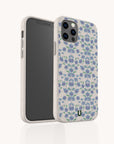The Blue Ditsy Flowers Eco-Friendly Biodegradable Phone Case features a blue and purple floral pattern on white, shown upright and at an angle to highlight its design and precise camera cutout.