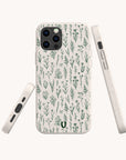 The Green Wild Flowers Eco-Friendly Phone Case is displayed from three angles—back, side, and bottom—to showcase its beige color with green botanical illustrations, as well as the floral design details and accurate cutouts for ports and buttons.