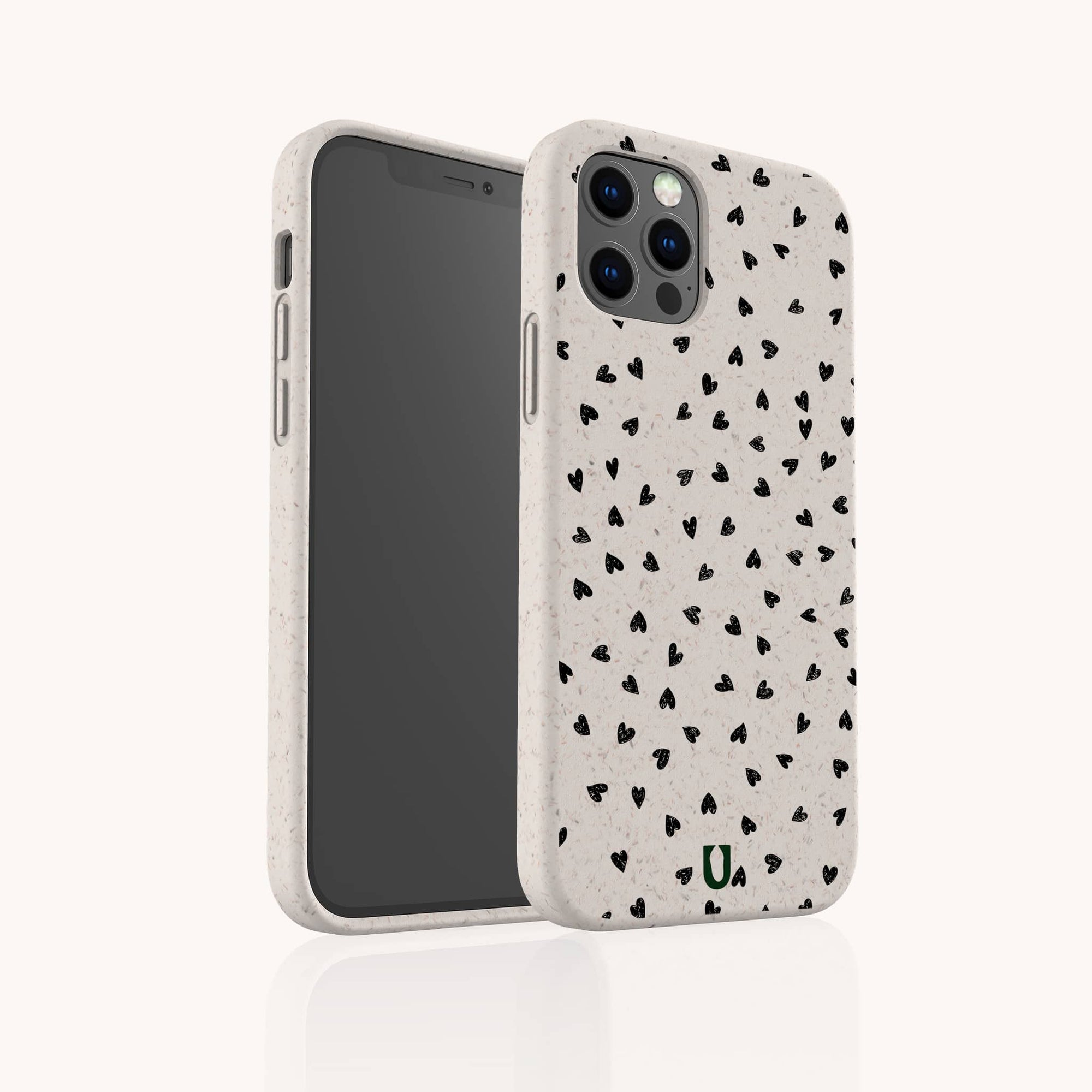 The Black Hearts Eco-Friendly Phone Case is beige with a scattered black heart pattern, covers the back and sides of your smartphone, and features cutouts for camera lenses and buttons. The case is biodegradable.