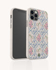 The Pink Ribbons Eco-Friendly Biodegradable Phone Case, featuring pink flowers, green ribbons, and blue lattice on white, is shown upright beside a smartphone, displaying both the floral design and the eco-conscious material.