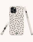 The Black Hearts Eco-Friendly Phone Case is biodegradable and has a white speckled background with a pattern of small black hearts. Images show the case from the back, side, and at an angle to highlight its design and button cutouts.