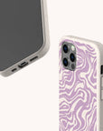 Showcasing two smartphones in beige cases, one presents the screen while the other reveals the Purple Marble Swirl Eco-Friendly Phone Case’s signature purple and white abstract wavy pattern on its textured back. Both cases feature visible cutouts for buttons and ports, blending stylish design with sustainable materials to support eco-friendly choices.
