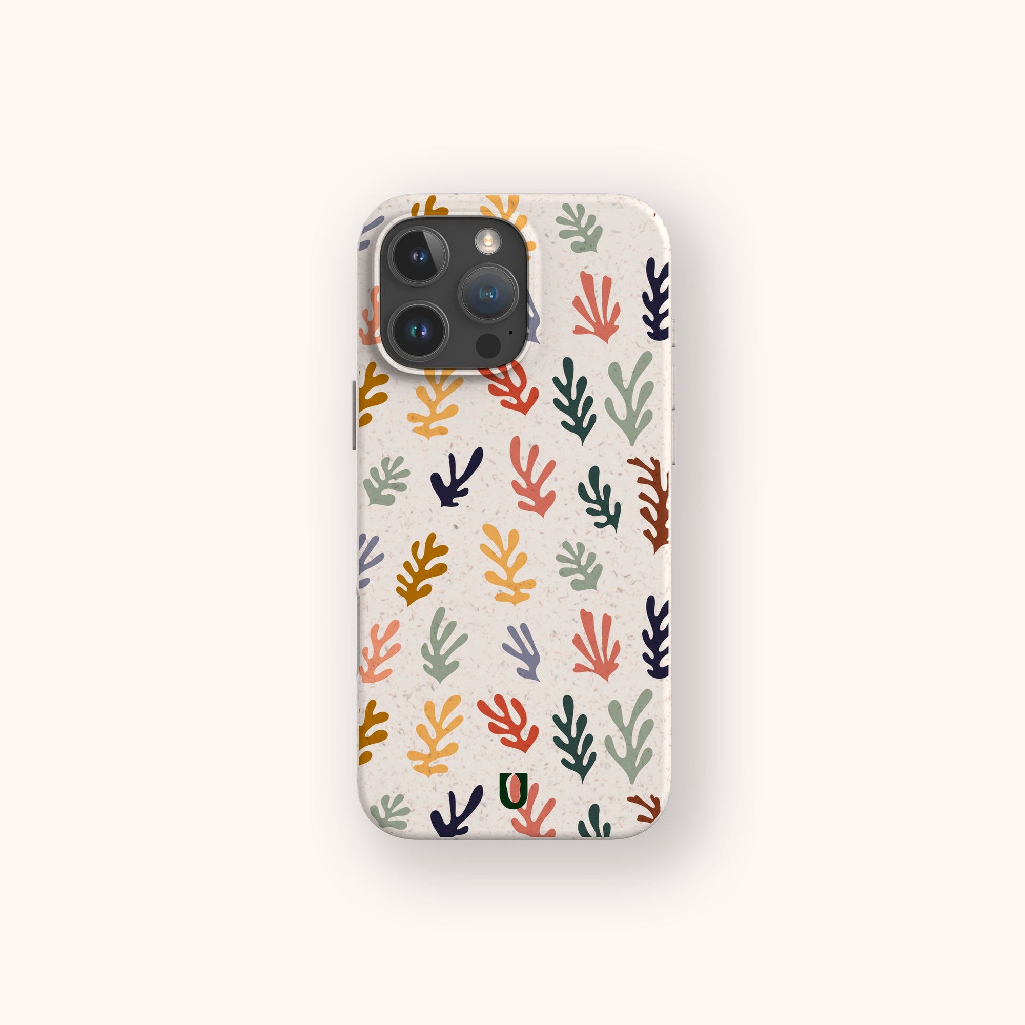 The Algae Eco-Friendly Phone Case, in beige with a colorful abstract coral pattern (red, green, blue, yellow, orange), is displayed on a light neutral background.