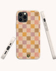 The Pink and Purple Checker Eco-Friendly Phone Case is shown from the back, side, and bottom. This compostable case features a pink and purple checkerboard pattern, rounded edges, and a small green horseshoe logo near the bottom.