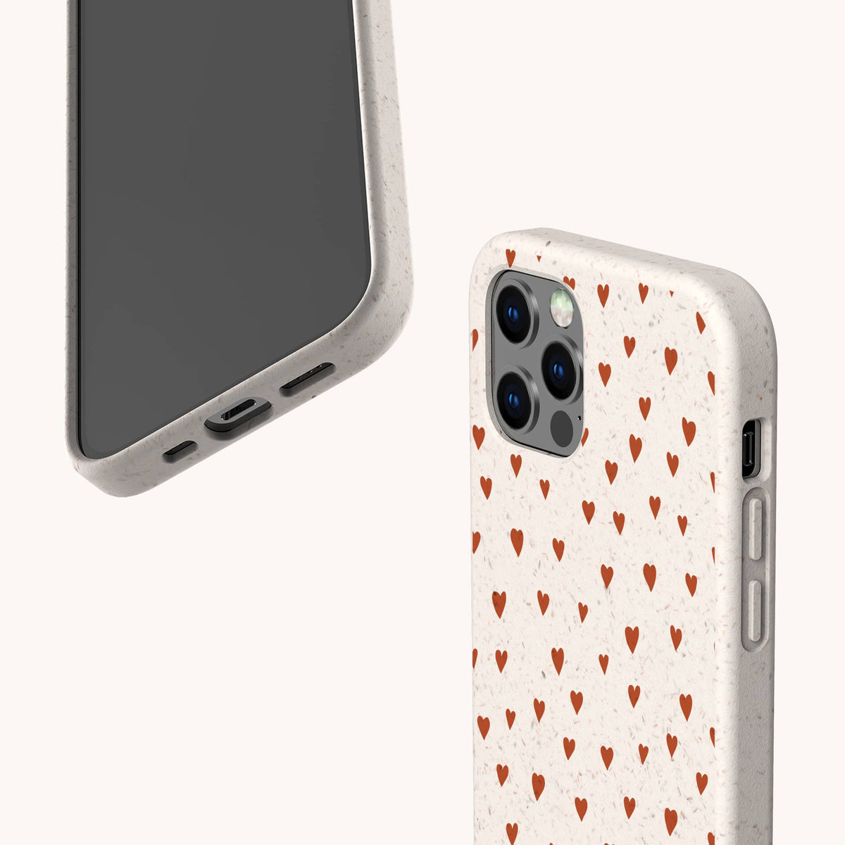 Two smartphones with beige cases: one, the Red Hearts Eco-Friendly Phone Case, features a repeating red heart pattern, while the other—displayed as a Samsung Galaxy case—shows the phone screen and charging port. Both cases have a smooth, matte texture.