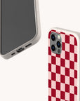 Two smartphones in speckled beige cases are displayed on a plain white background; one features the Red and Pink Checker Eco-Friendly Biodegradable Phone Case with a distinctive checkerboard pattern, while the other showcases the phone’s screen and charging port.