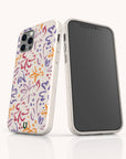 Two smartphones in white are protected by Flower Strokes Eco-Friendly Phone Cases featuring vibrant, abstract floral patterns in orange, purple, and red. One phone displays the back of the case with the colorful design, while the other shows the front screen. Both phones stand on a white surface.