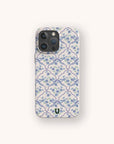A smartphone with the Blue Flowers and Bow Ribbons Eco-Friendly Biodegradable Phone Case, featuring a coquette design with a blue and white floral tile pattern, small green leaves, and a black U logo at the bottom center.