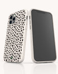Two smartphones—one in an iPhone and the other in a Samsung Galaxy case—are displayed against a plain background, each featuring the Dark Spots Eco-Friendly Phone Case with a white minimalist design and black irregular dot patterns reminiscent of a dalmatian print. One phone highlights the stylish back of the case, while the other displays its screen.
