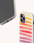 Two phones in beige cases: one has horizontal watercolor stripes in pink, orange, and purple (Summer Rainbow Eco-Friendly Phone Case), while the other is a plain speckled beige, both made from compostable materials for iPhone and Samsung models.