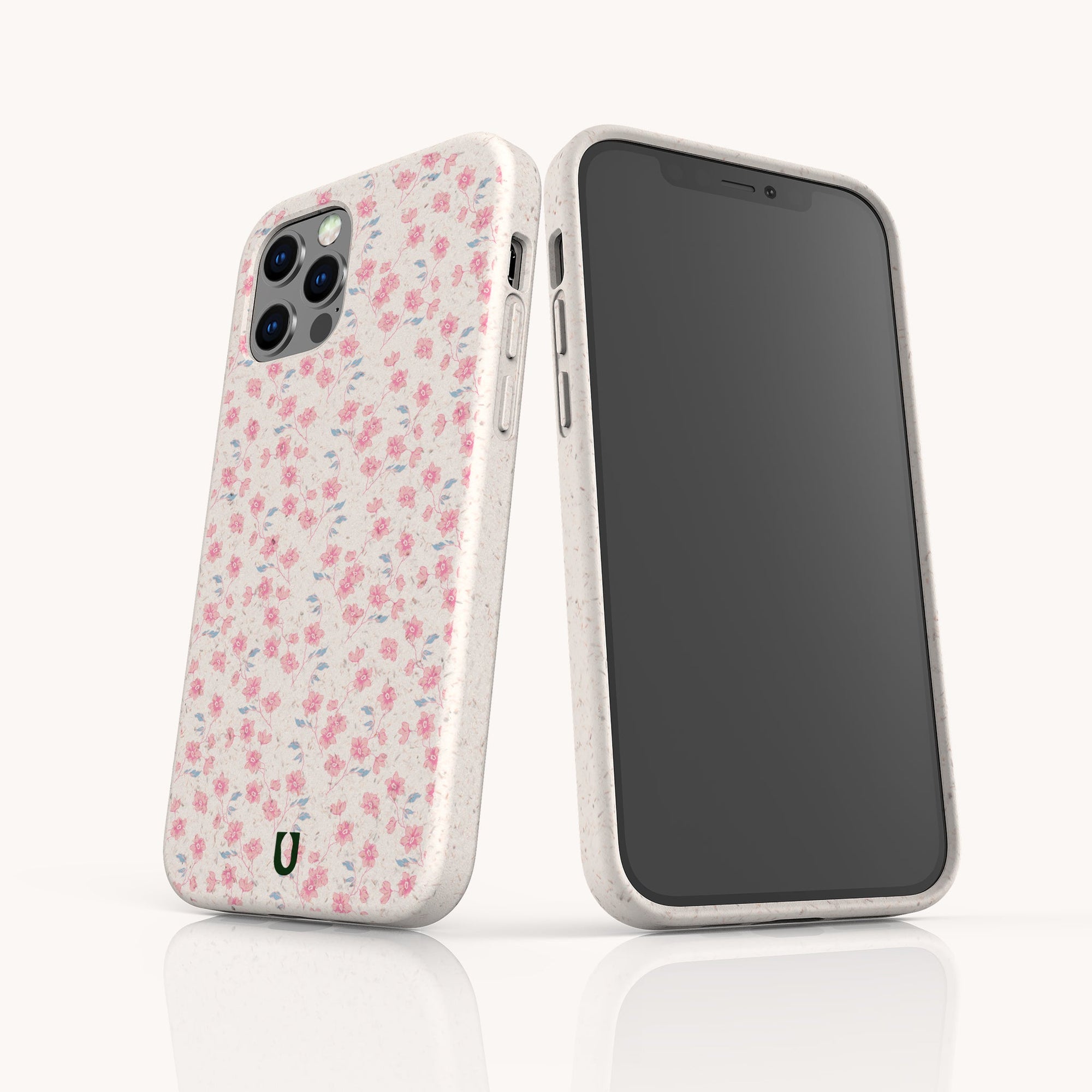 Two smartphones with the Pink Ditsy Flowers Eco-Friendly Biodegradable Phone Case are displayed—one shows the floral pattern, the other a blank screen. Both cases stand upright on a reflective white surface, ideal for eco-conscious buyers.