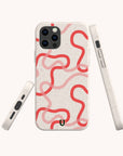 Three views of the Pink and Red Swirls Eco-Friendly Biodegradable Phone Case on a smartphone, showcasing its beige speckled, plant-based material and bold and thin wavy red lines looping across the back, photographed against a plain light background.