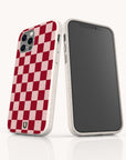 Two smartphones with beige cases are shown; one features the Red and Pink Checker Eco-Friendly Biodegradable Phone Case, showcasing a bold red and pink checkerboard pattern on the back, while the other displays a blank black screen from the front.