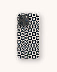 Centered on a light background, the Black Flower Checker Eco-Friendly Phone Case is displayed on a smartphone. The case features a black and white grid pattern with each square containing a simple white flower with a black center.