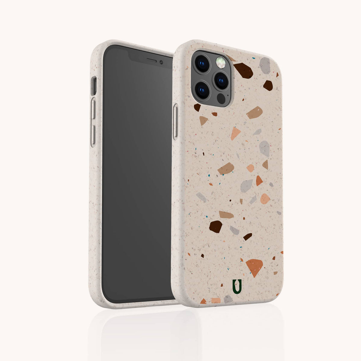 The Terrazzo Print Eco-Friendly Phone Case in beige, featuring a pattern of brown, gray, and orange specks, is shown on a smartphone standing upright and slightly angled to display both the front screen and the unique back design.