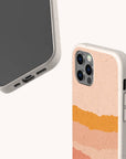 Two smartphones in beige Valleys Eco-Friendly Phone Cases—crafted from sustainable materials; one displays the front screen, while the other reveals the back, showcasing a pink, peach, and orange layered abstract design. Both phones are set against a plain light background.