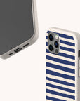 Two smartphones with beige cases are shown. One features the Navy Stripes Eco-Friendly Biodegradable Phone Case, decorated with blue horizontal lines; the other displays the phone’s screen and charging port. Both eco-friendly cases appear against a light background.