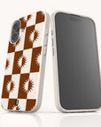 Two smartphones featuring the Sunseeker Eco-Friendly Biodegradable Phone Case in white, adorned with a brown and white checkerboard pattern and sunburst accents on the back. One phone highlights the stylish back design, while the other displays its sleek black screen. Crafted from sustainable materials, these cases are perfect for anyone seeking an eco-friendly option without sacrificing style.