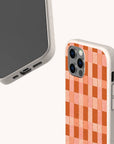 Two smartphones with beige, compostable Terracotta Watercolour Checker Eco-Friendly Phone Cases. The back case features a red and pink checkerboard pattern reminiscent of watercolour art. One phone displays the screen and ports, while the other showcases the camera and patterned back. These sustainable cases are compatible with iPhone and Samsung models, perfectly blending eco-friendly design with artistic style.