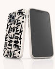 Two Love Words Eco-Friendly Biodegradable Phone Cases are displayed side by side; one highlights the back featuring the word LOVE printed repeatedly in bold black letters, while the other shows the front screen. These white cases have a speckled texture and are thoughtfully crafted to offer a stylish, planet-friendly accessory option.