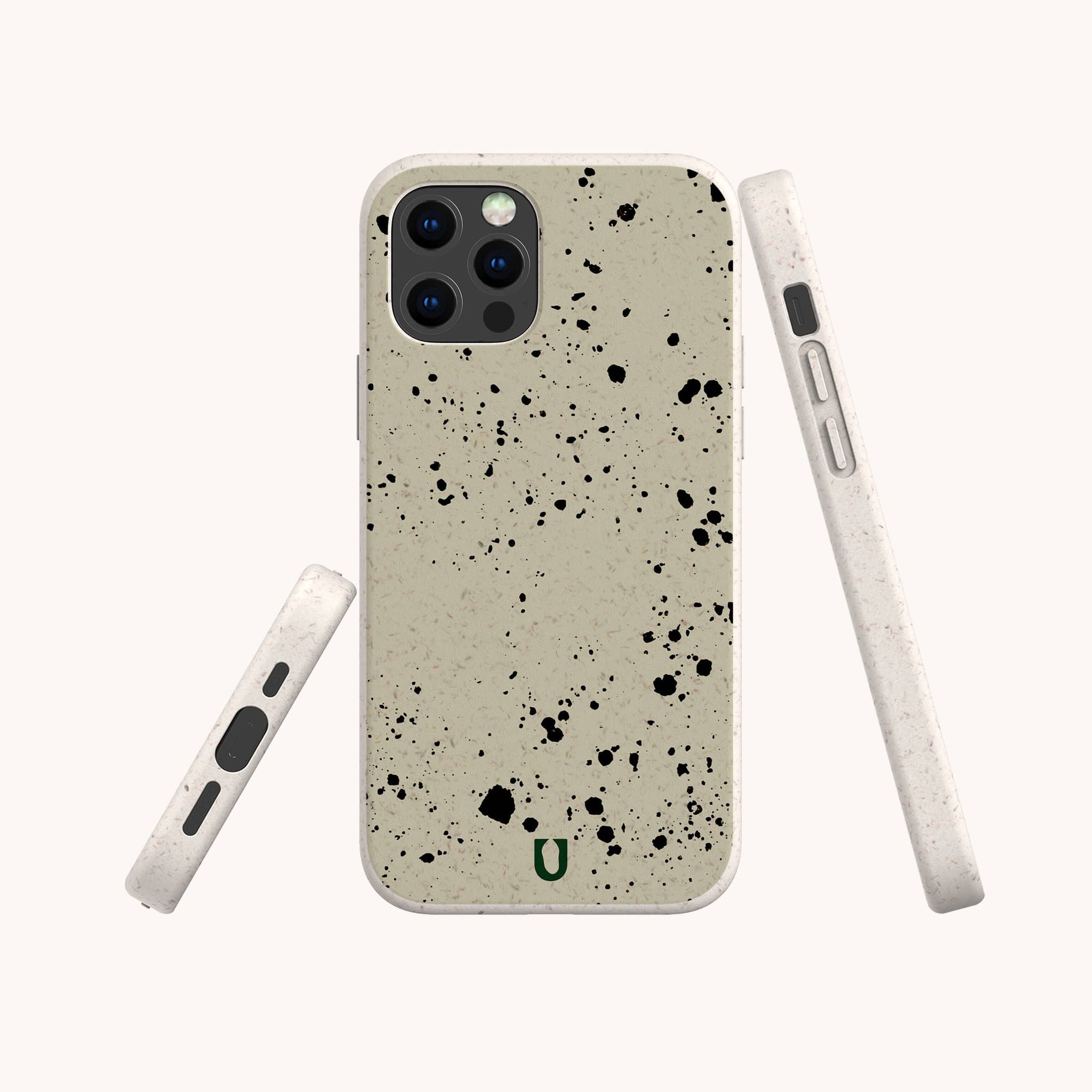 The Grunge Eco-Friendly Phone Case in beige with urban black splatter is shown from the back, side, and bottom. Cutouts fit camera, buttons, and charging port. A small green horseshoe logo features at the bottom center.