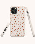 Three Red Hearts Eco-Friendly Phone Cases in beige are displayed from various angles. Each iPhone case features a small green horseshoe-shaped logo near the bottom, adding a unique touch to this eco-friendly design.