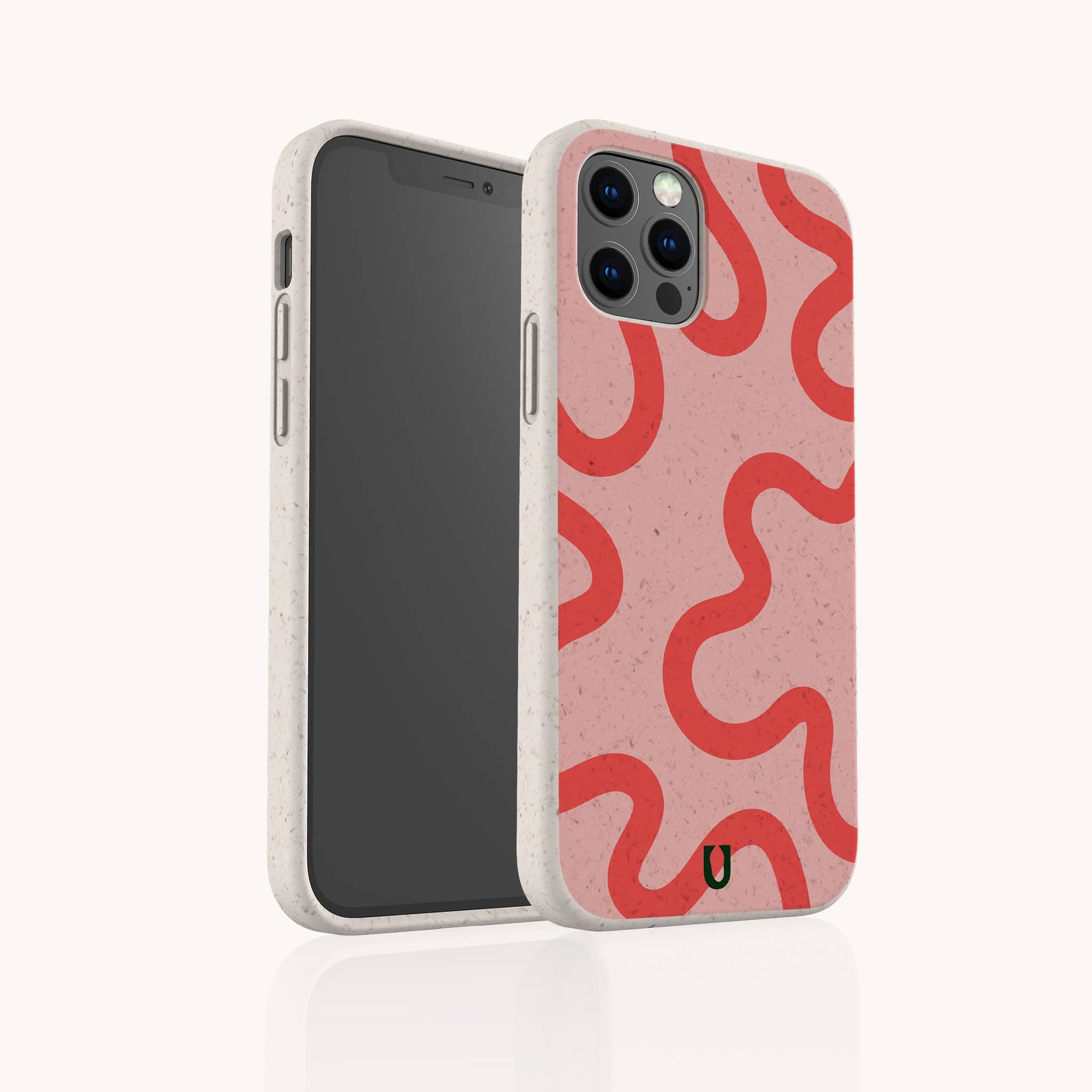 The Red and Pink Swirl Lines Eco-Friendly Phone Case features a pink, biodegradable design with bold red wavy lines, speckles, and a black "U" logo near the bottom. It fits iPhone and Samsung Galaxy models. The phone screen is black and turned off.
