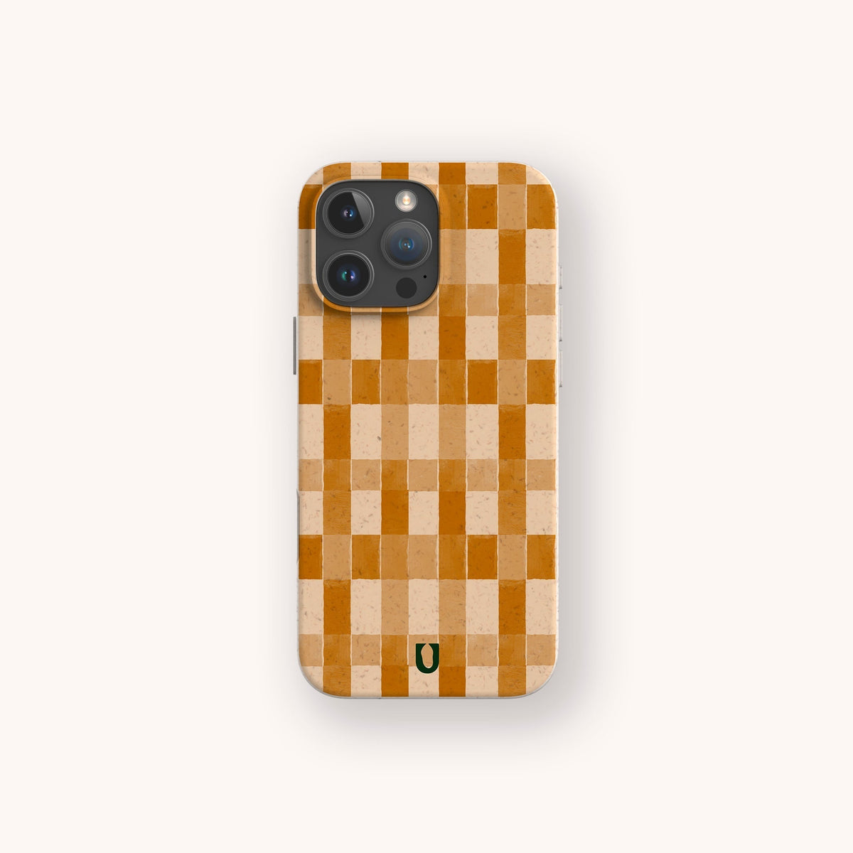 A smartphone is shown with the Brown Watercolour Checker Eco-Friendly Phone Case, which features a brown checker pattern and a small green horseshoe symbol at the bottom center. The case complements the device’s three rear cameras and is displayed against a light background.