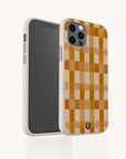 The Brown Watercolour Checker Eco-Friendly Phone Case, featuring a brown and beige checkerboard pattern, stands upright to showcase its sustainable style and camera-side design. Compatible with iPhone and Samsung models.