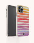 The Summer Rainbow Eco-Friendly Phone Case features colorful, uneven stripes in yellow, orange, red, pink, and purple on beige compostable material with a speckled texture and small black logo. Compatible with iPhone and Samsung.